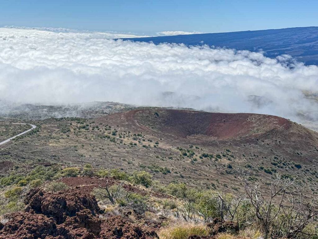 A view of a volcanic crater just above the clouds on the Puโu Kalepeamoa Trail - Mauna Kea Visitor Information Station.