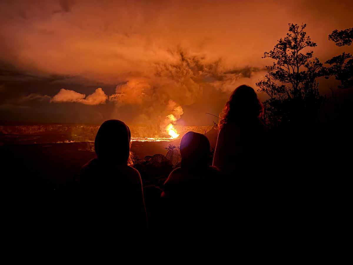 Celine Brewer, owner of FamilyCanTravel.com, watches the Kilauea volcano erupt with her kids in the dark at Hawaii Volcanoes National Park on the Big Island.