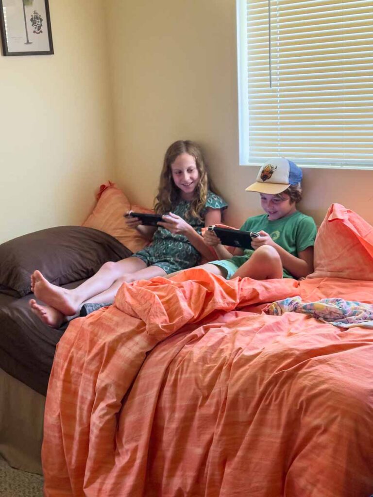 Two kids enjoy playing on their Nintendo Switch consoles at their VRBO in Volcano, Hawaii.