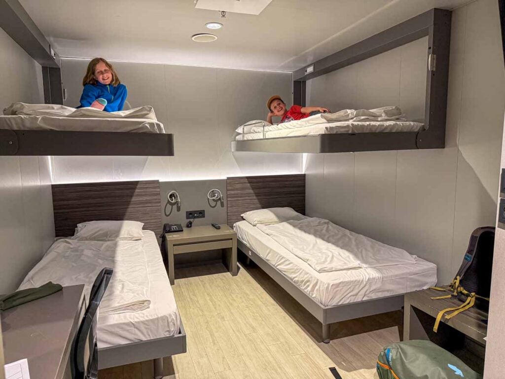 The Brewer kids, from the FamilyCanTravel.com, blog lie on their beds in a 4-bed room on the overnight ferry from Athens to Crete.