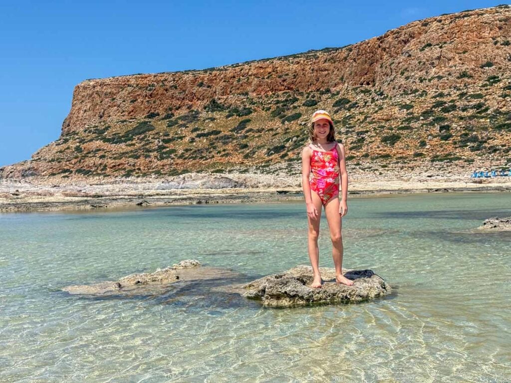 An 1--year old girl plays in the warm water at Balos Beach, Crete, Greece.