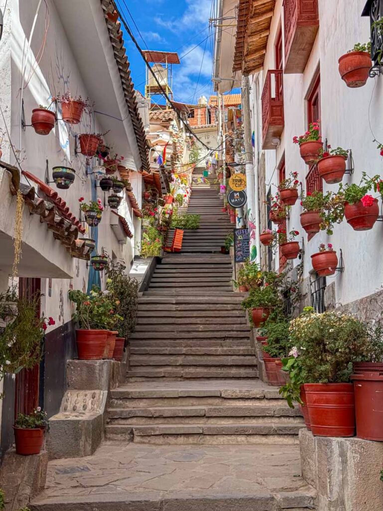 Colorful potted plants line the white walls of Siete Borreguitos - considered as one of the most beautiful streets in Cusco, Peru.