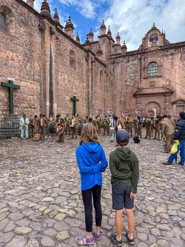 The Brewer kids from the Family Can Travel blog, watch a band play as part of a festival in front of the Cusco Cathedral.