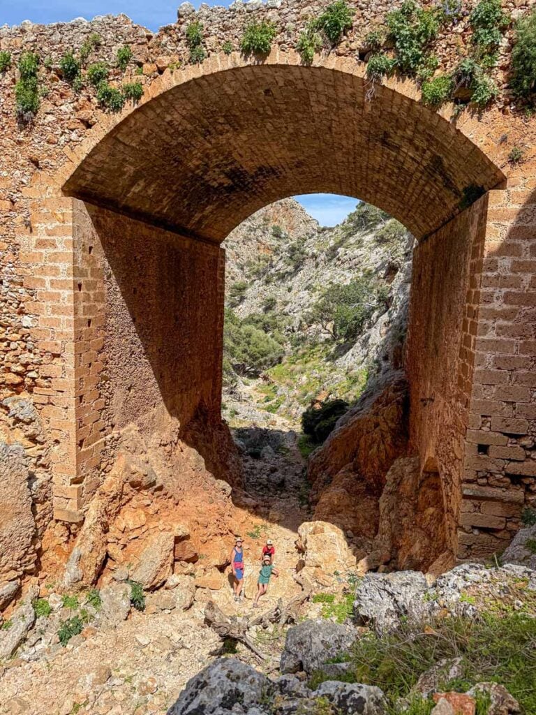The Brewer family stands under the Katholiko Monastery bridge while on a family-friendly hike in Crete.