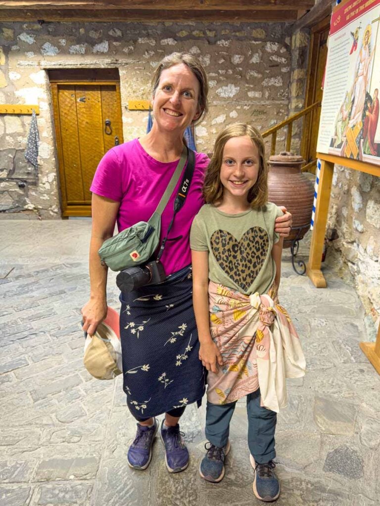 Celine Brewer, from the Family Can Travel blog, poses with her daughter wearing borrowed skirts at the Monastery of St. Stephen in Meteora, Greece.
