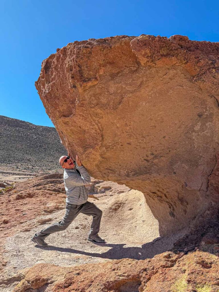 Dan Brewer, co-owner of FamilyCanTravel.com, plays around with a giant rock while visiting the Ollagüe Volcano Viewpoint during a family tour of the Uyuni Salt Flats.