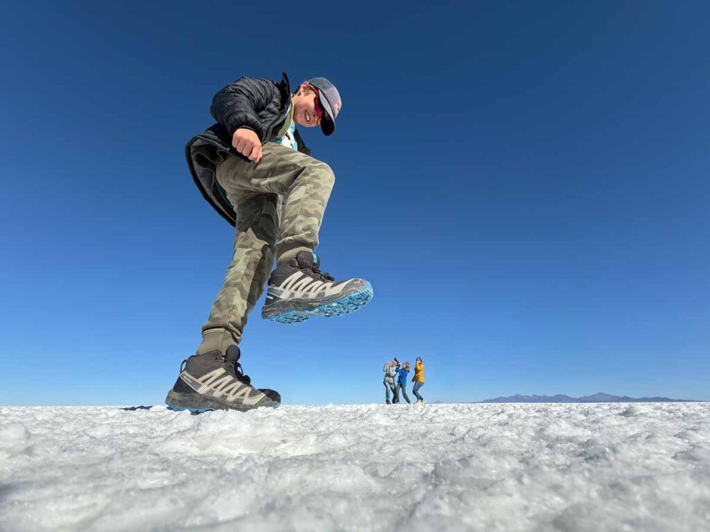 a 9-year old boys "stomps" his family in a forced perspective picture at the Uyuni Salt Flats in Bolivia.