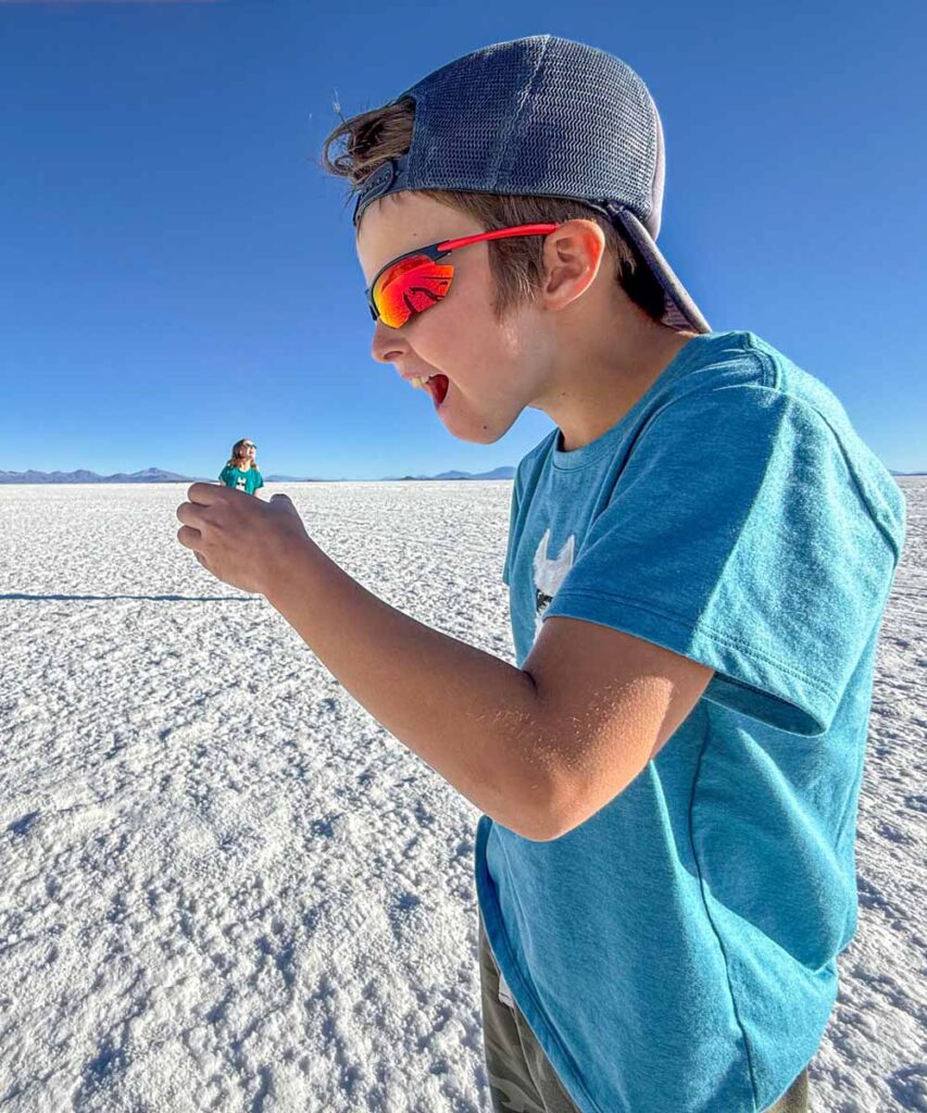A 9 year old boy looks like he is eating his bigger sister in a forced perspective picture in the Uyuni Salt Flats, Bolivia.