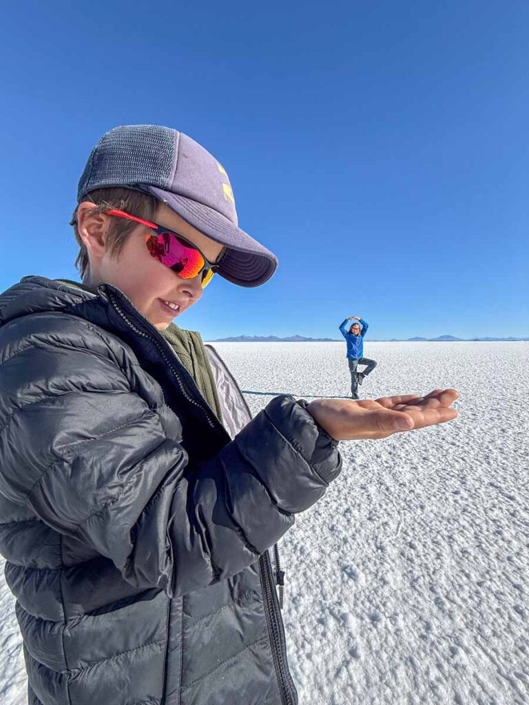 A 9-year old boy appears to be holding his big sister in the palm of his hand in a forced perspective photo while on a family trip to the Uyuni Salt Flats, Bolivia.