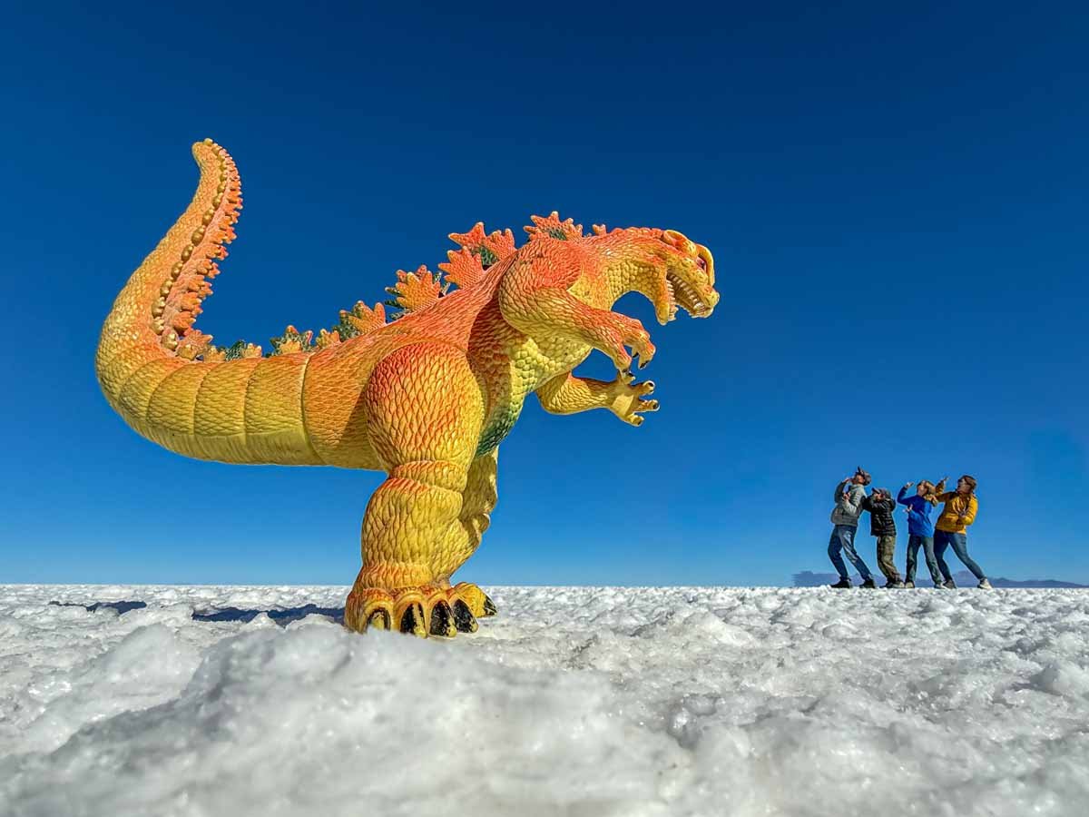 The Brewer family, from the FamilyCanTravel.com blog, pose for a forced perspective photo with a giant dinosaur in the Uyuni Salt Flats in Bolivia.