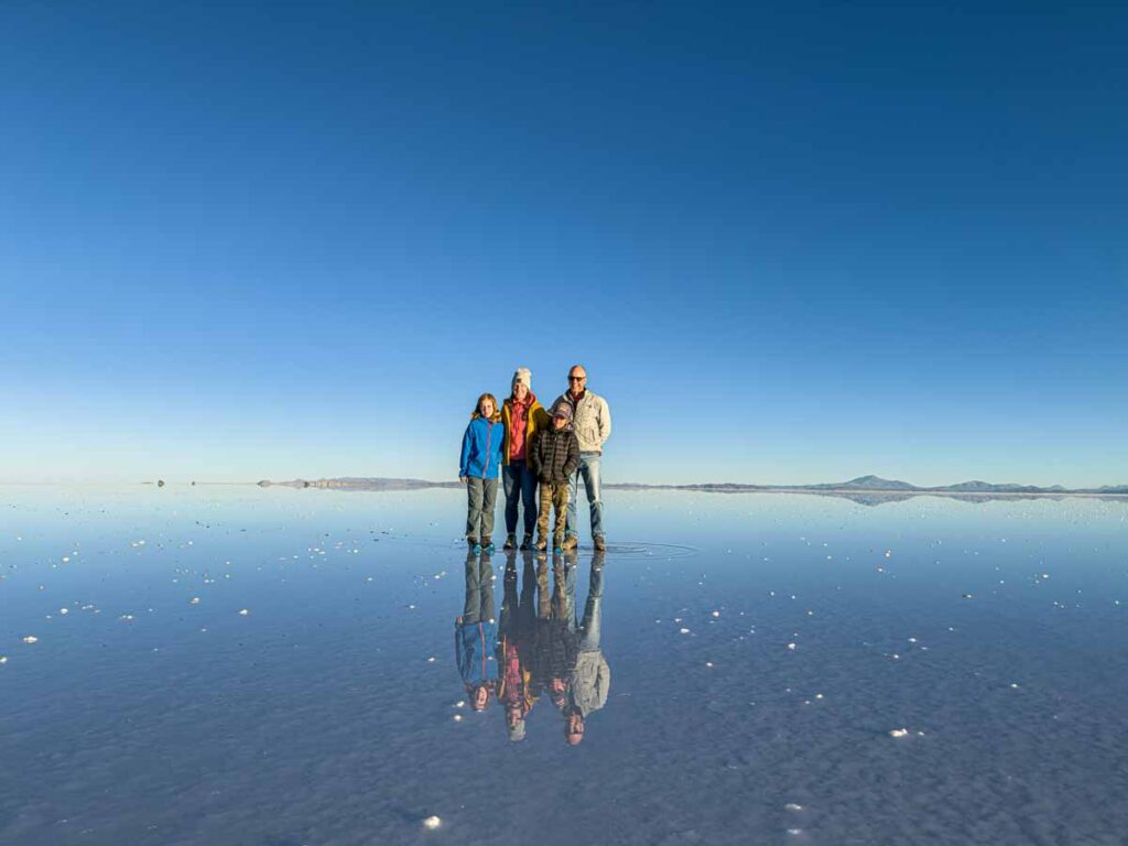 Dan and Celine Brewer, owners of FamilyCanTravel.com, get a family photo taken with the famous mirror effect at the Uyuni Salt Flats in Bolivia.