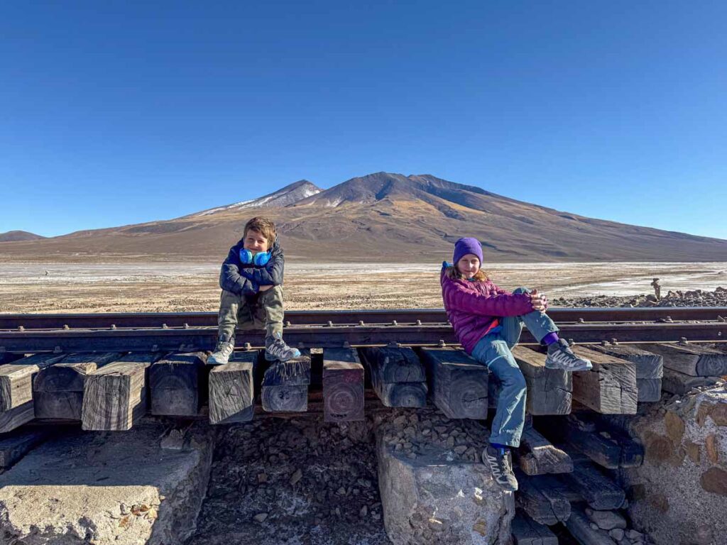 the Brewer kids, from the Family Can Travel blog, sit on a railway bridge on a 3-day family-friendly tour of the Uyuni Salt Flats in Bolivia.