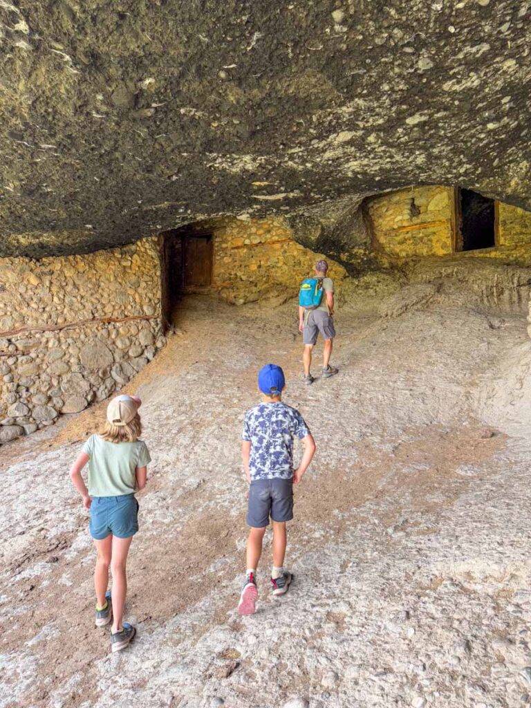 Dan Brewer, owner of FamilyCanTravel.com, explores a hermitage with his kids during a family hiking trip to Meteora, Greece.
