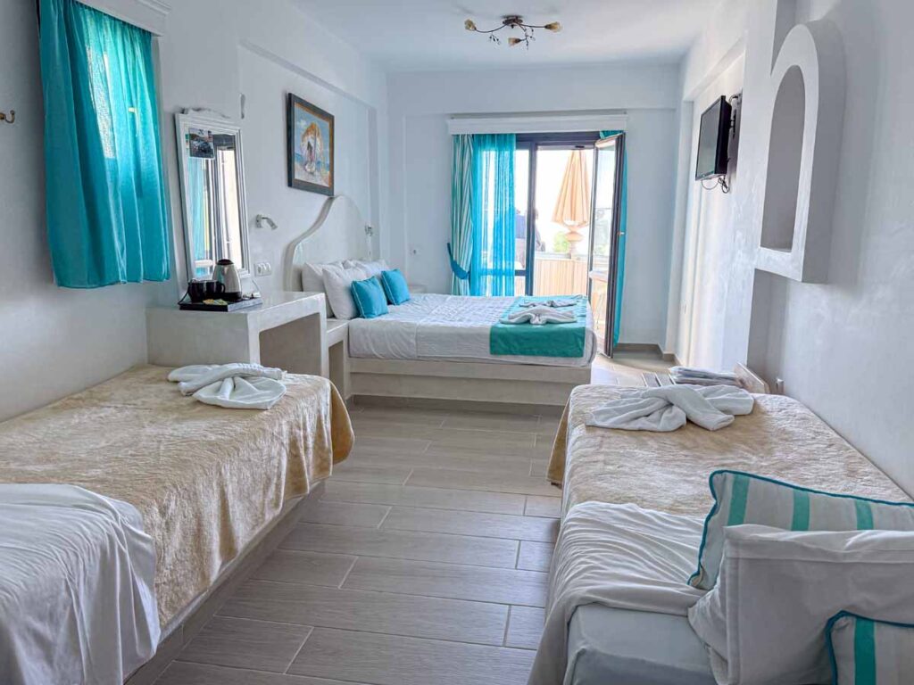 a family room with three beds at the family-friendly Ellinon Thea Hotel in Santorini, Greece.