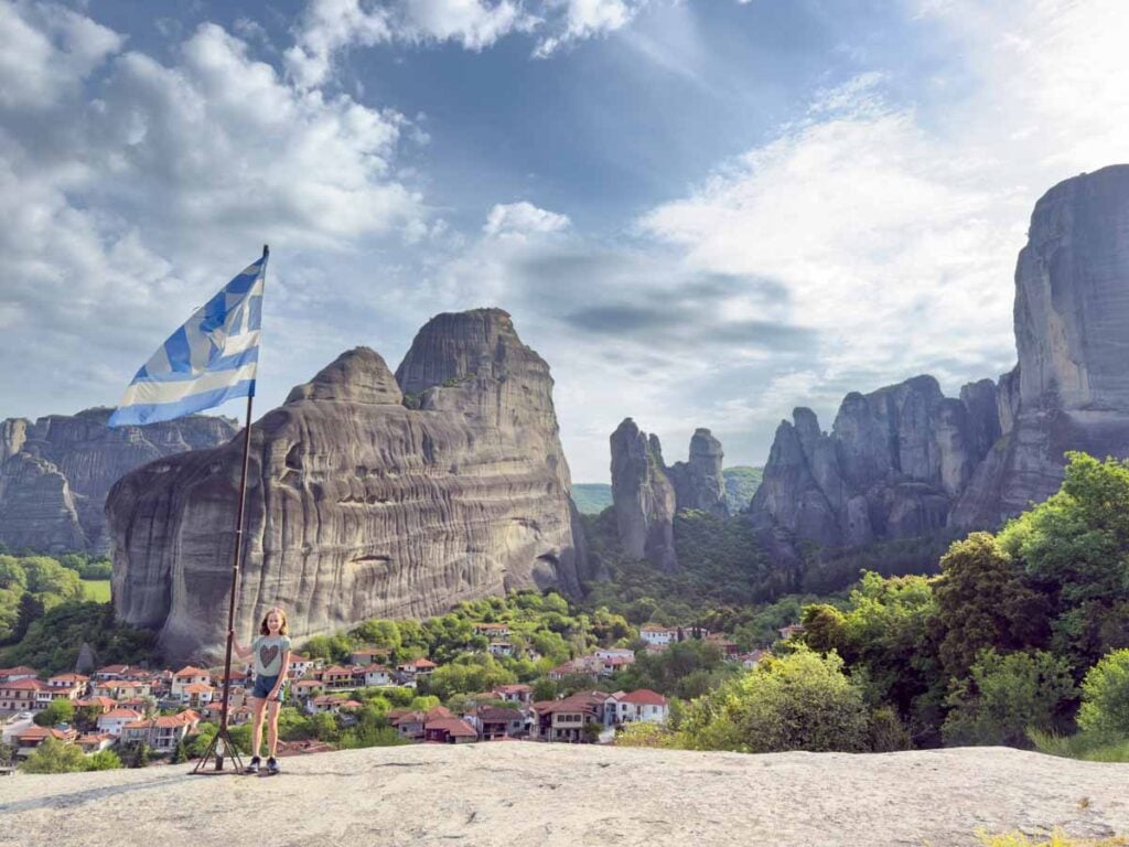 an 11-year old girl stands with the Greek flag while on a family hike in Meteora, Greece.