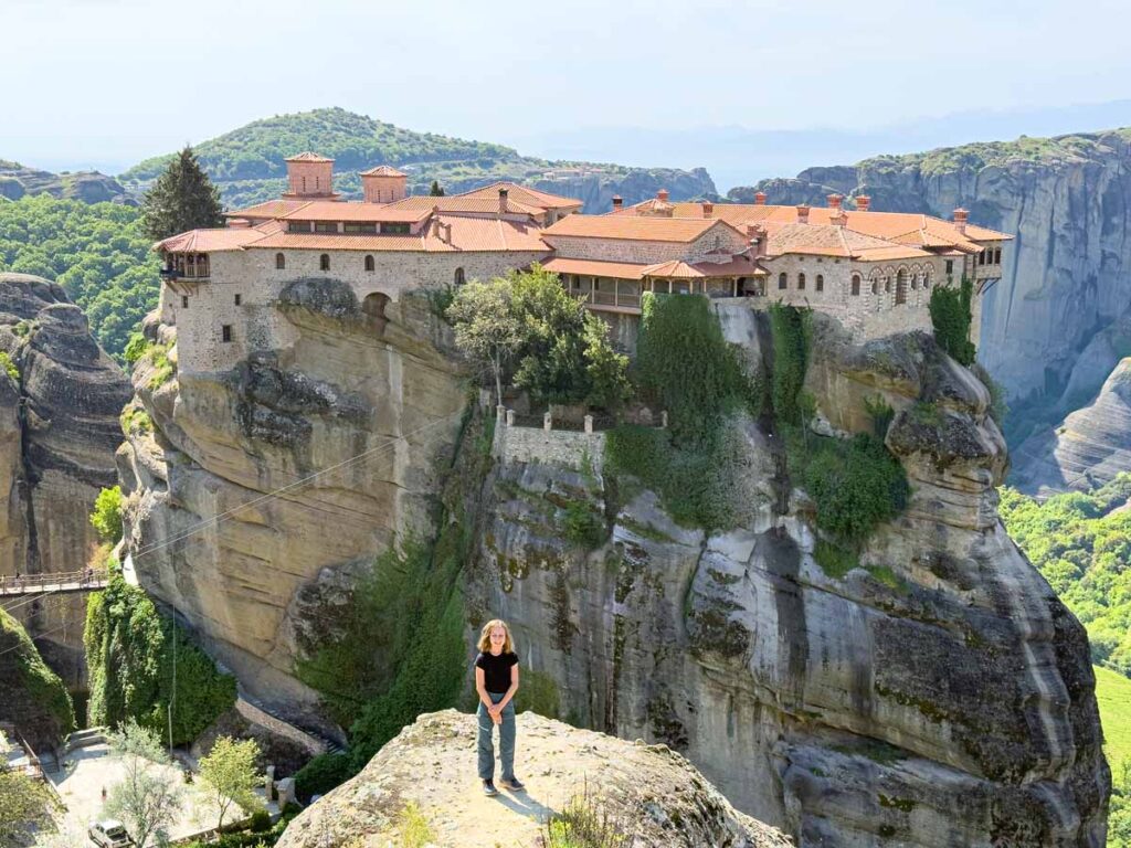 an 11-year old girl stands in front of the Holy Monastery of the Great Meteoron while on a family hiking trip to Meteora, Greece.