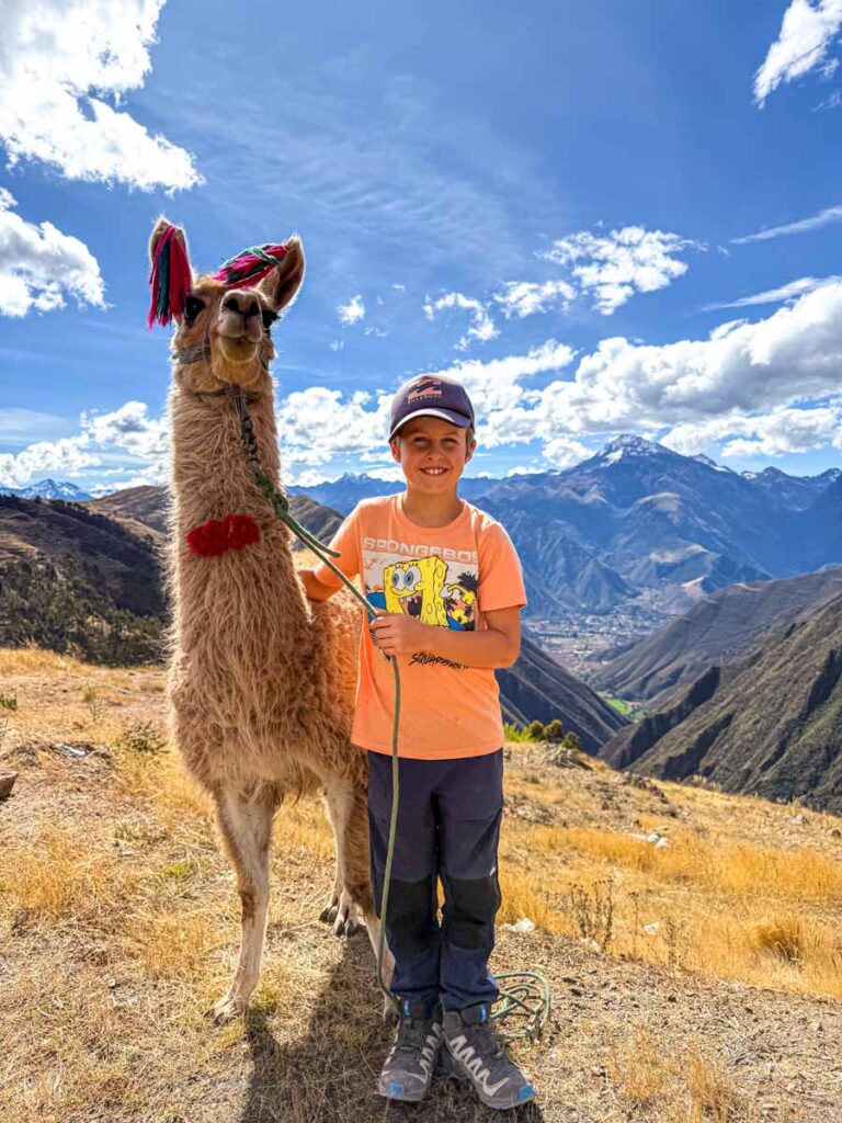 a 9-year old boy with his llama while on a family-friendly hiking with llamas tour in Cusco, Peru.