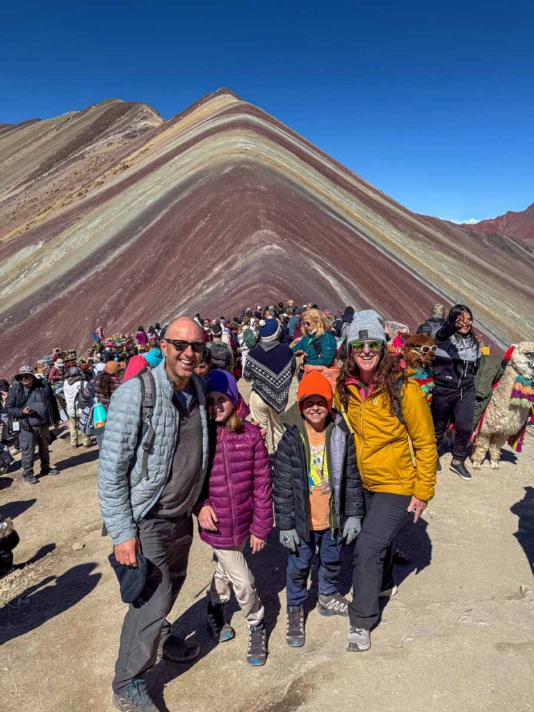 The Brewer family, from the Family Can Travel website, reaches the top of a very bust Rainbow Mountain while on a family vacation in Cusco, Peru.