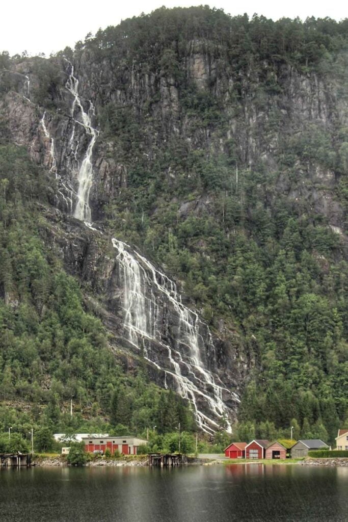 a massive waterfall behind a small village as seen on the fjord tour to Mostraumen from Bergen.