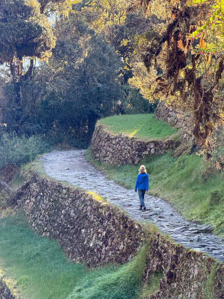 an 11-year old girl hikes past the Conchamarca ruins on Day 2 of her family-friendly Inca Trail hiking tour.