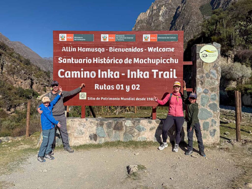 The Brewer family, from the Family Can Travel blog, visits the km 82 sign at the beginning of their family trek on the Inca Trail to Machu Picchu.