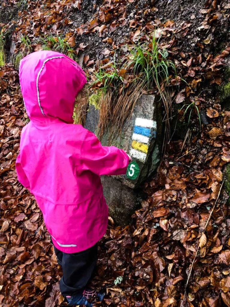 a 4-year old girl on a family trip to Karlovy Vary, stops to look at trail markers on the hike to the Diana Lookout.
