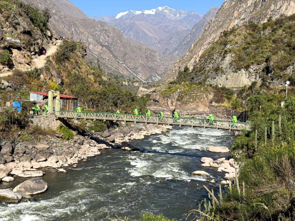 Porters carry equipment on a bridge over the Urubamba River at the beginning of the Inca Trail near km 82.
