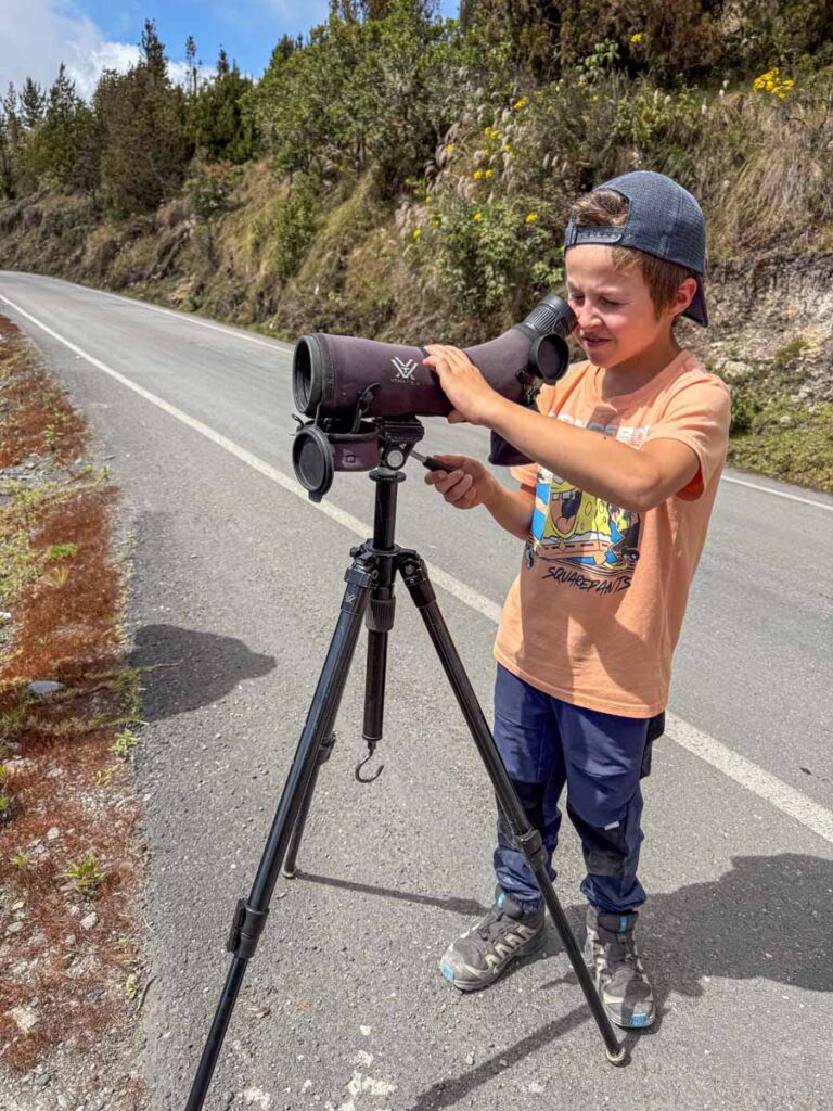 a 9-year old boy looks for toucans through a bird spotting scope on a family-friendly tour of Manu National Park.