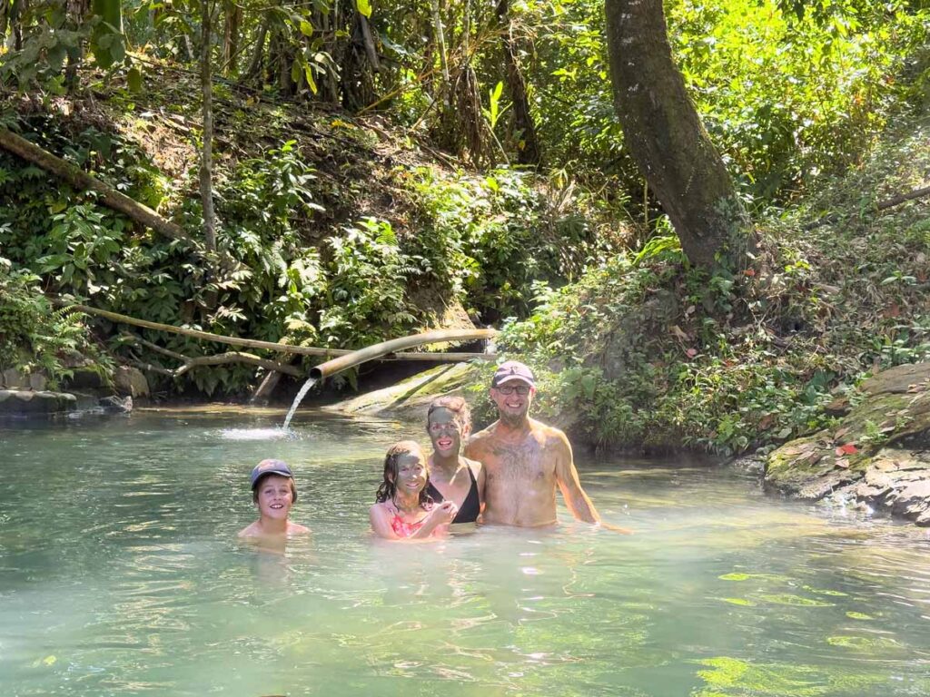 The Brewer family, from FamilyCanTravel.com, enjoy rubbing mud on their faces at a natural hot spring while on a family-friendly tour to Manu National Park.