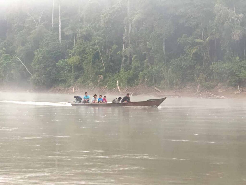 a local boat rides on the river surrounded by dense fog near Manu National Park.