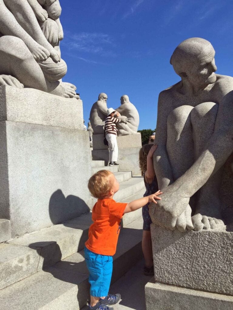 a 2-year old boy looks at a sculpture in the Vigeland Sculpture Park while on a family vacation to Oslo, Norway.