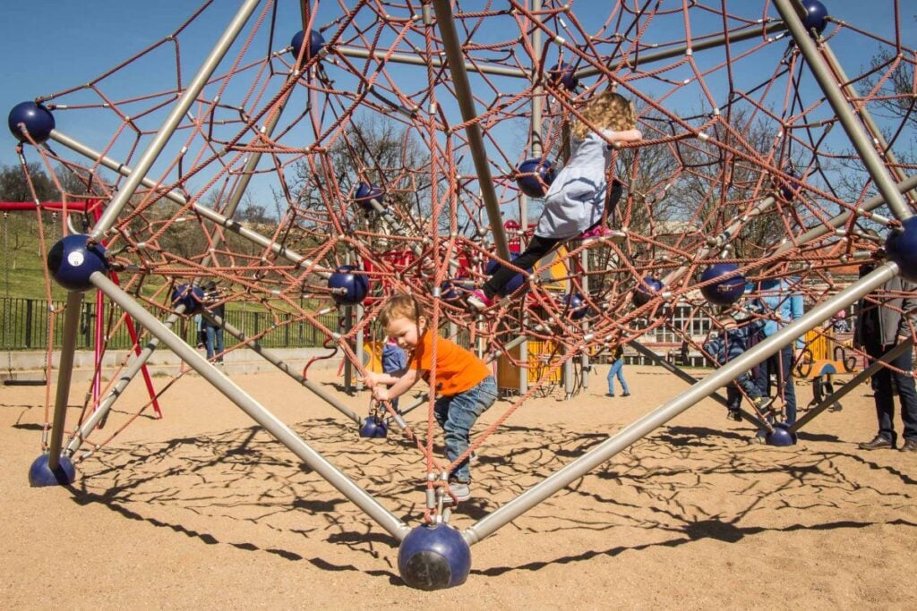 a 2-year old on a family trip to Prague plays in a playground in Petrin Park.