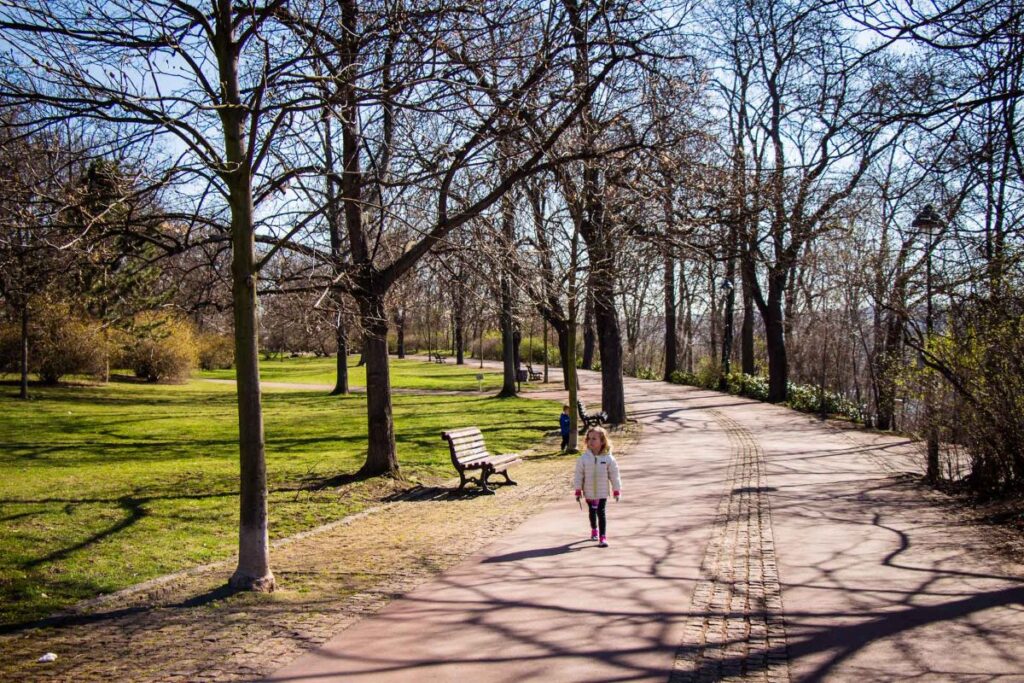Two small kids on a family trip to Prague enjoy a family walk in Letna Park on a spring day in April.