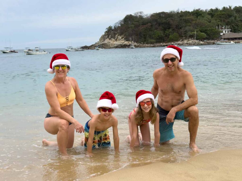 Dan and Celine Brewer, owners of FamilyCanTravel.com, pose for a family photo with Santa hats on Christmas Day in Puerto Escondido.