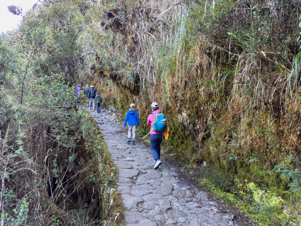 Celine Brewer, owner of FamilyCanTravel.com, hikes on a section of hte Inca Trail with her kids that has been carved into the side of a very steep cliff.