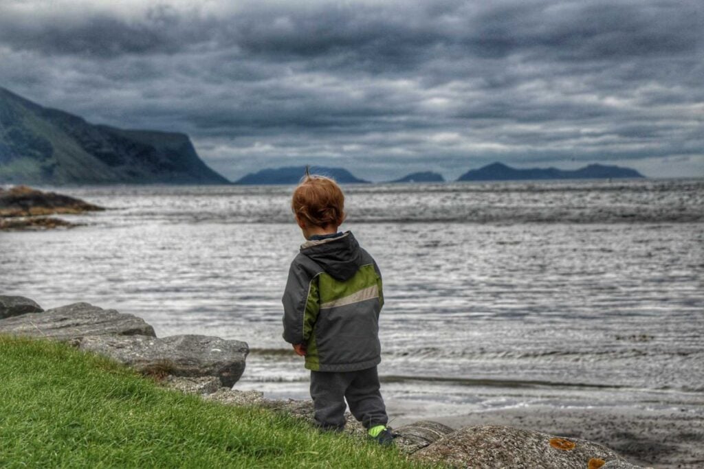 a 2-year old boy on a family trip to Alesund, walks near the ocean in Tueneset Naturlekeplass.