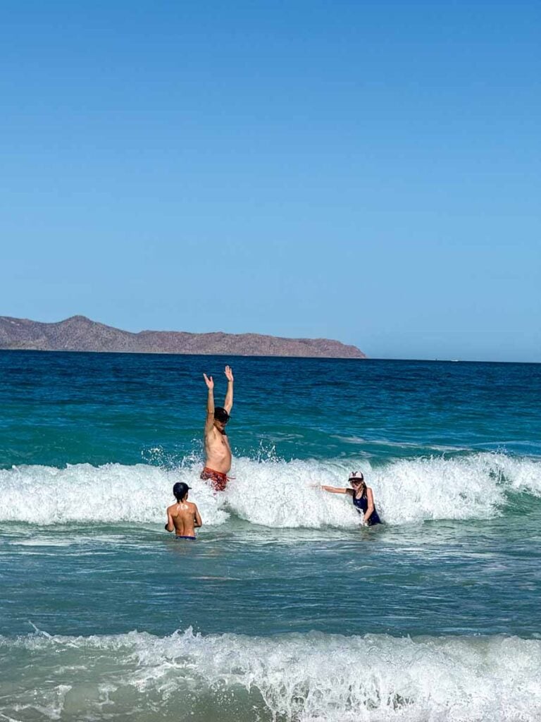 Dan Brewer, owner of FamilyCanTravel.com, plays in the waves with his kids at Playa el Tecolote on a family trip to La Paz, Mexico.