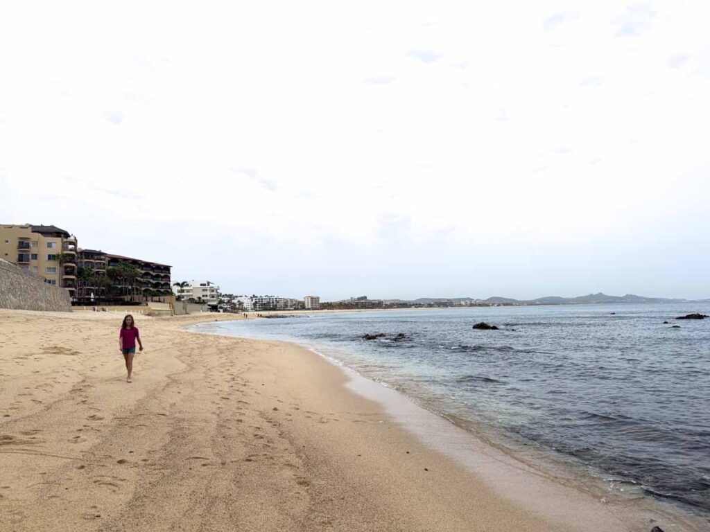 a 12-year old girl on a family holiday to San Jose del Cabo walks along Costa Azul Beach on a cloudy, windy day.