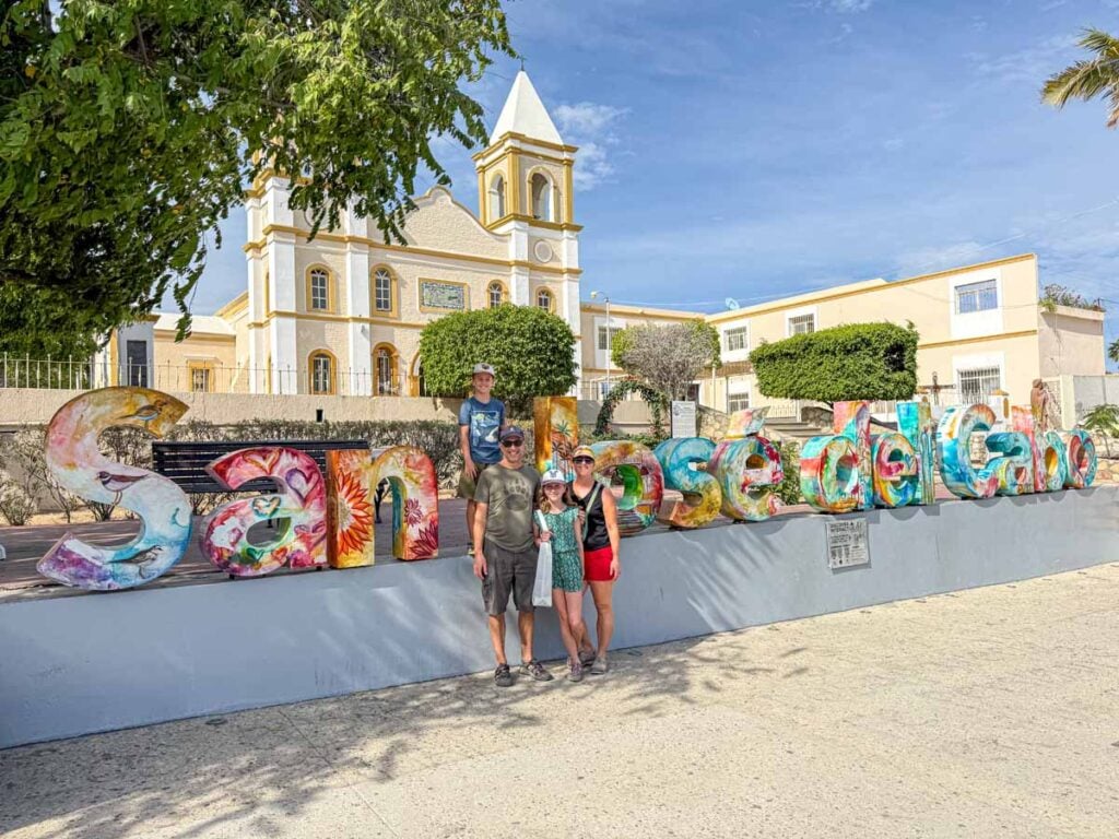 The Brewer family, from the Family Can Travel blog, stands near the colorful San Jose del Cabo sign near the Mision San Jose del Cabo church.