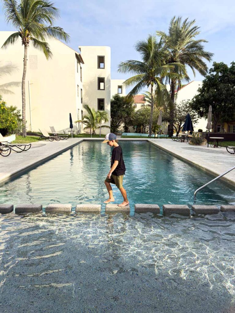 a 10-year old boy walks on a stone path across the swimming pool at this family-friendly hotel in San Jose del Cabo, Mexico.