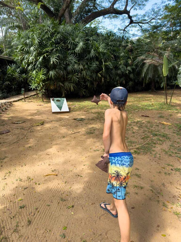 a young boy on a family trip to San Ignacio, Belize plays cornhole at the Sweet Songs Lodge.