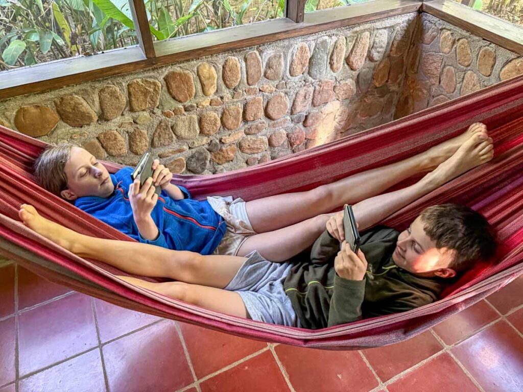 The Brewer kids, from FamilyCanTravel.com, read their e-readers while sharing a hammock in their Double Queen Bungalow at the Sweet Songs Jungle Lodge in Belize.