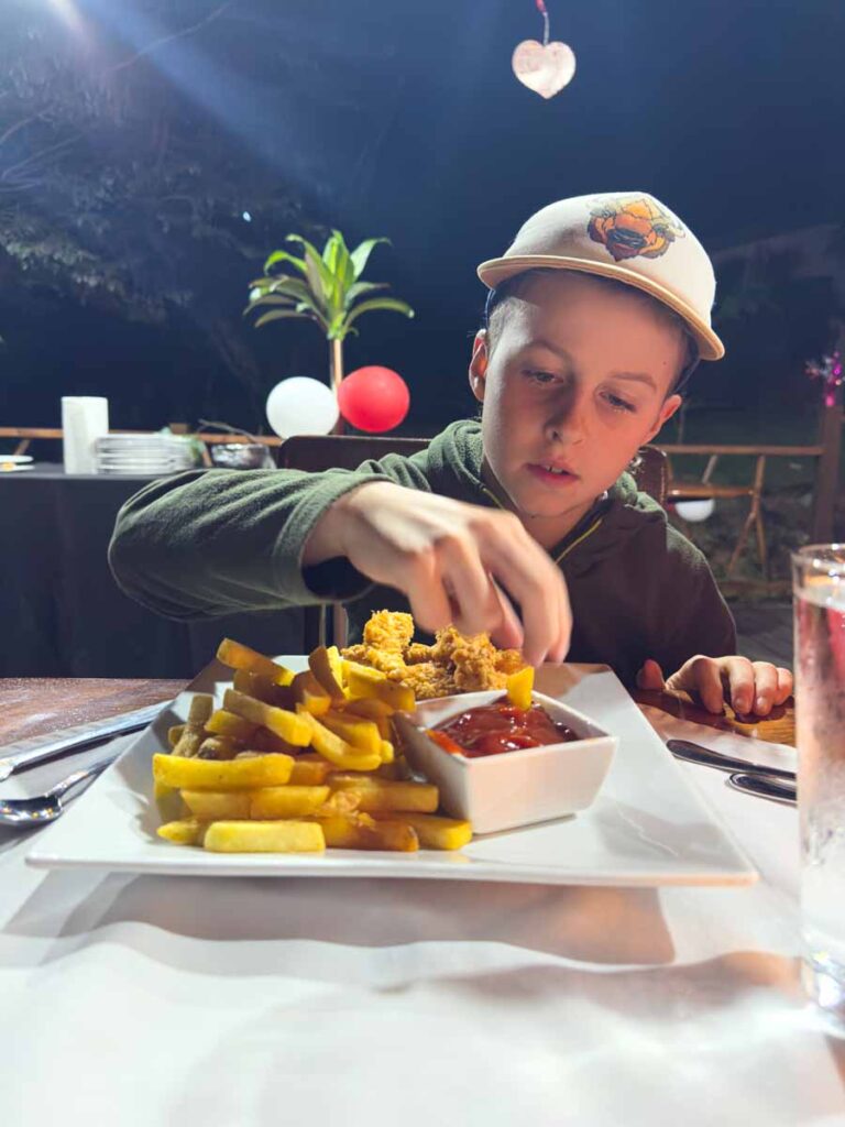 a picky 10-year old boy enjoys a hamburger at the Sweet Songs Jungle Lodge in San Ignacio, Belize.