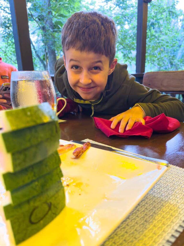 a 10-year old boy shows how much watermelon he ate for breakfast during a family trip to the Sweet Songs Jungle Lodge, Belize.