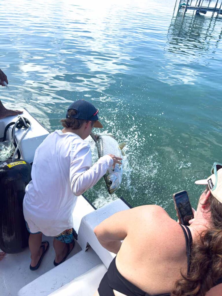 a 10-year old boy on a family trip to Ambergris Caye feeds the tarpon fish on a full day snorkeling tour.