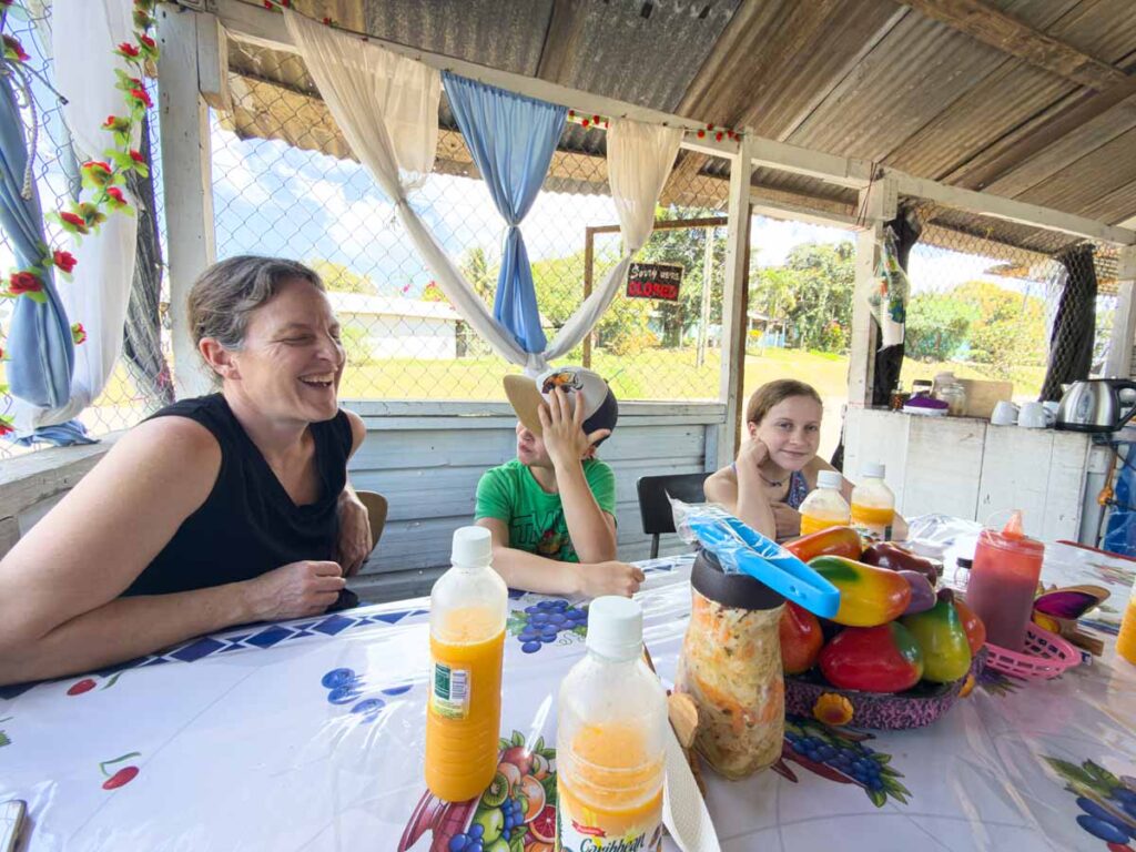 Celine Brewer, owner of the Family Can Travel blog, sits with her kids in an El Salvadorian restaurant after our cave tubing tour at Blue Hole National Park.