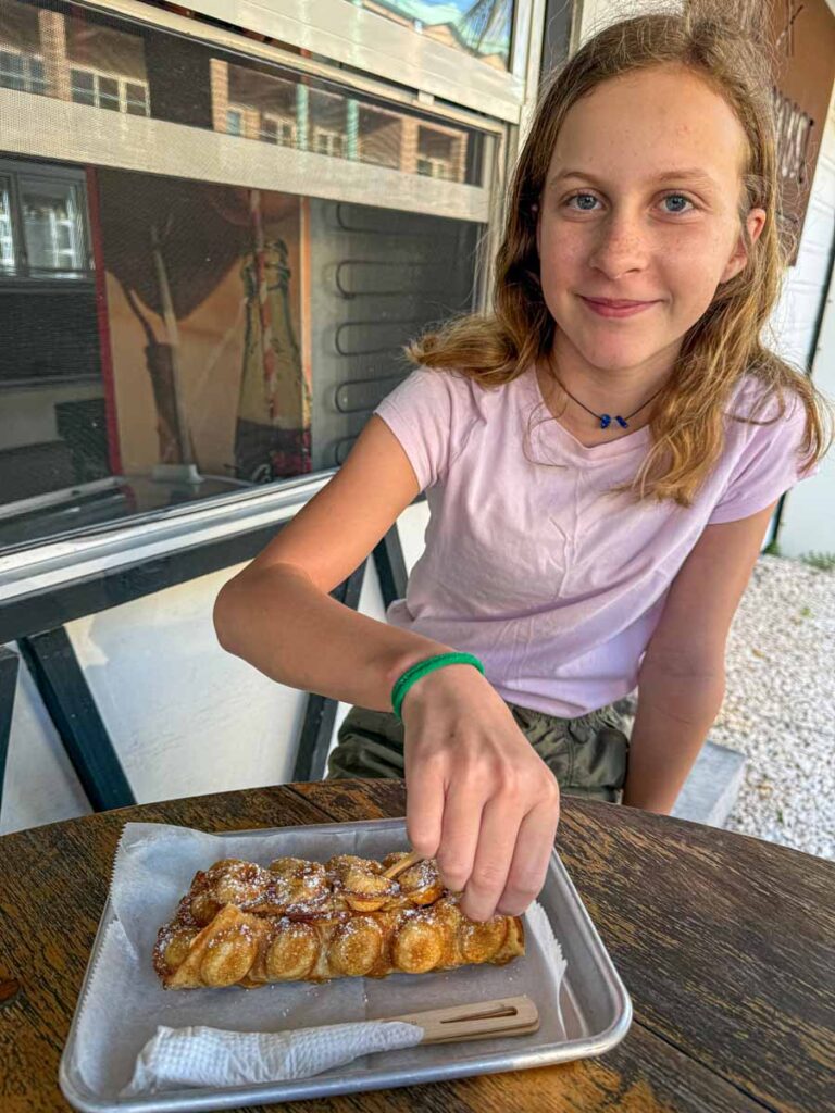 a 12-year old girl on a family trip to Ambergris Caye eats a bubble waffle at the Farmhouse Market.