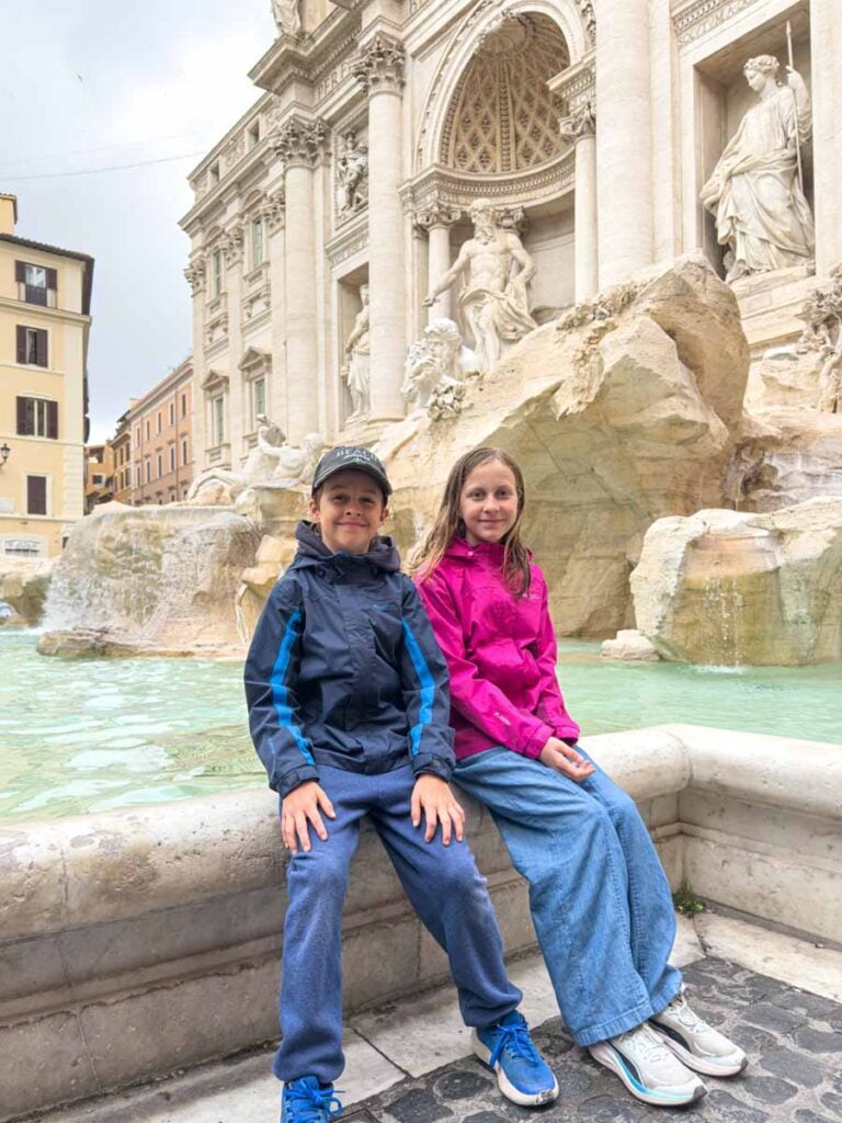 The Brewer kids sit next to the Trevi Fountain on an early morning visit during a family trip to Rome.
