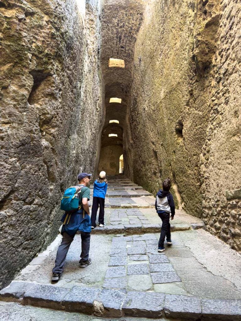 Dan Brewer, owner of the Family Can Travel blog, walks the dramatic entrance to the Aragonese Castle with his kids during a family holiday in Ischia.