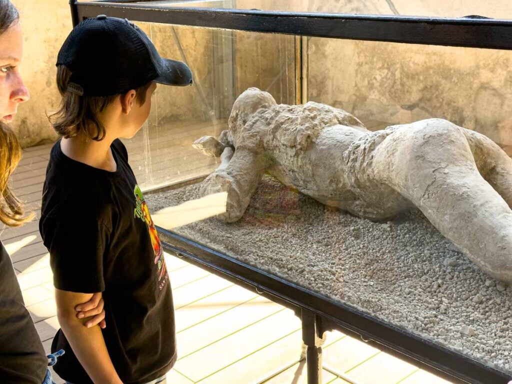 The Brewer kids, from the Family Can Travel blog, look at a plaster cast body while on a family trip to Pompeii, Italy.